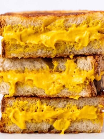 Three halves of a vegan grilled cheese sandwich stacked on top of each other.