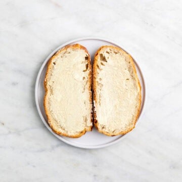 Two slices of bread spread with vegan butter on a plate.