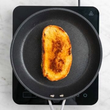 Vegan grilled cheese sandwich cooking in a skillet.