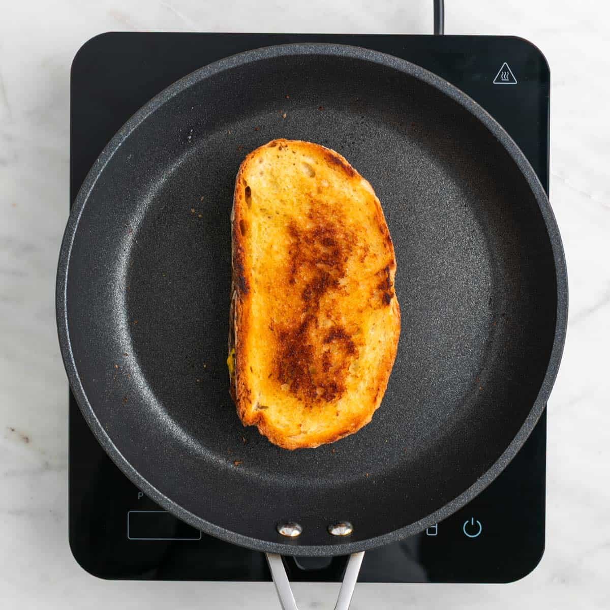 Vegan grilled cheese sandwich cooking in a skillet.