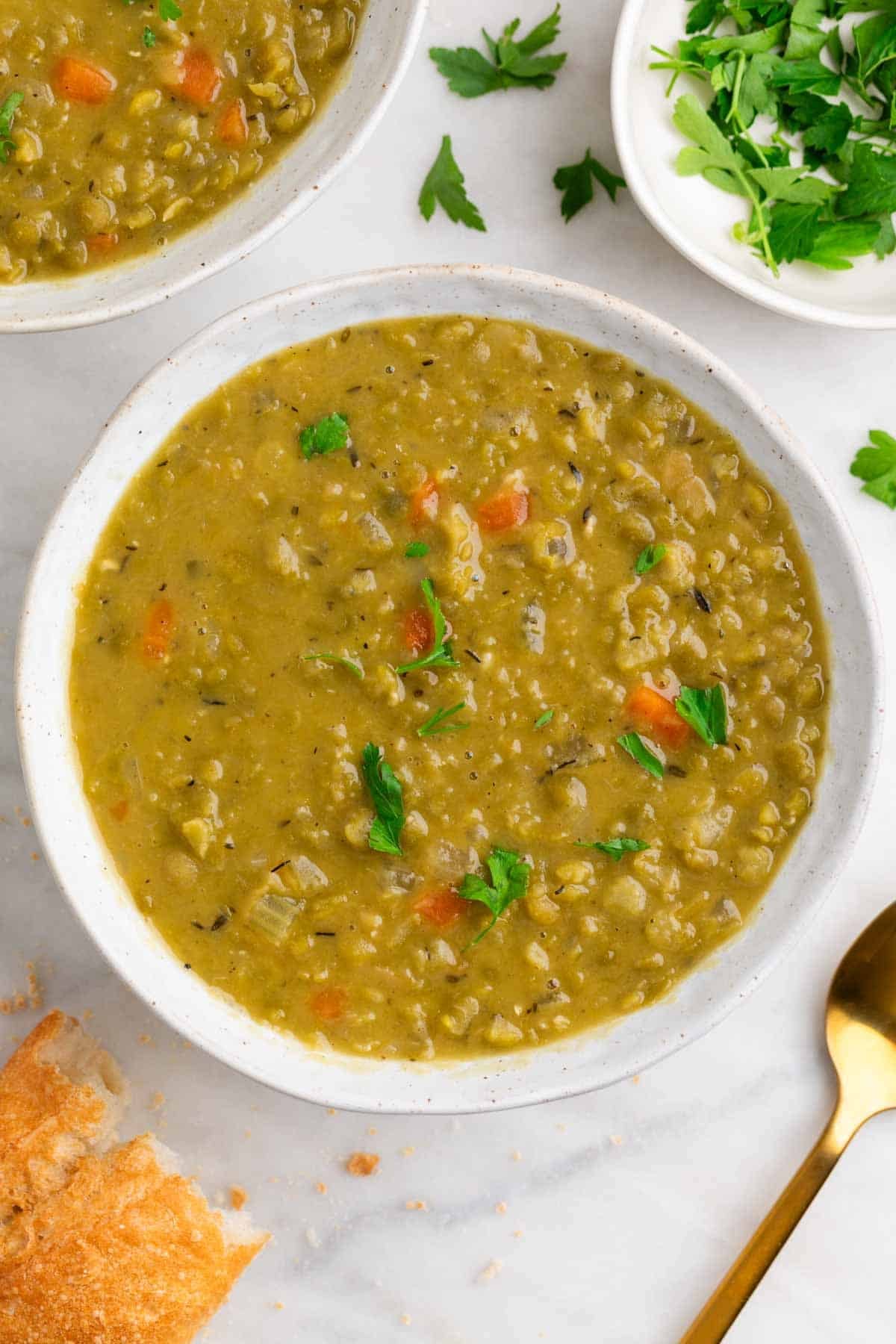 Vegan split pea soup with bread, parsley, and a spoon.