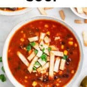 Overhead view of tortilla soup topped with cilantro and lime.