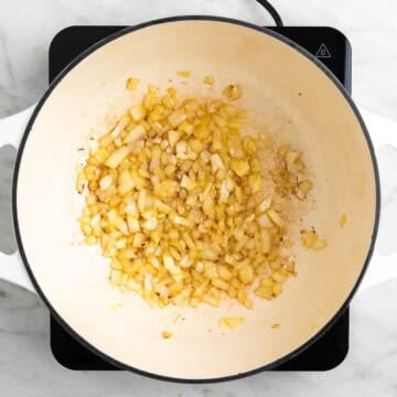 Chopped onion cooking in olive oil in a large pot.