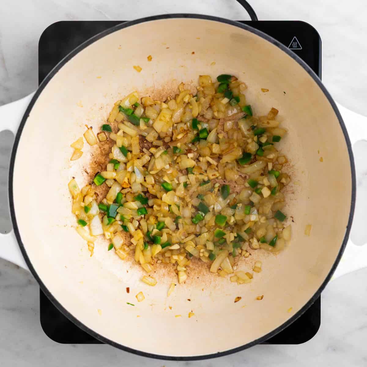 Onion, garlic, and jalapeño sautéing in a pot.