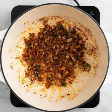 Onion, garlic, jalapeño, and spices cooking together in a pot.