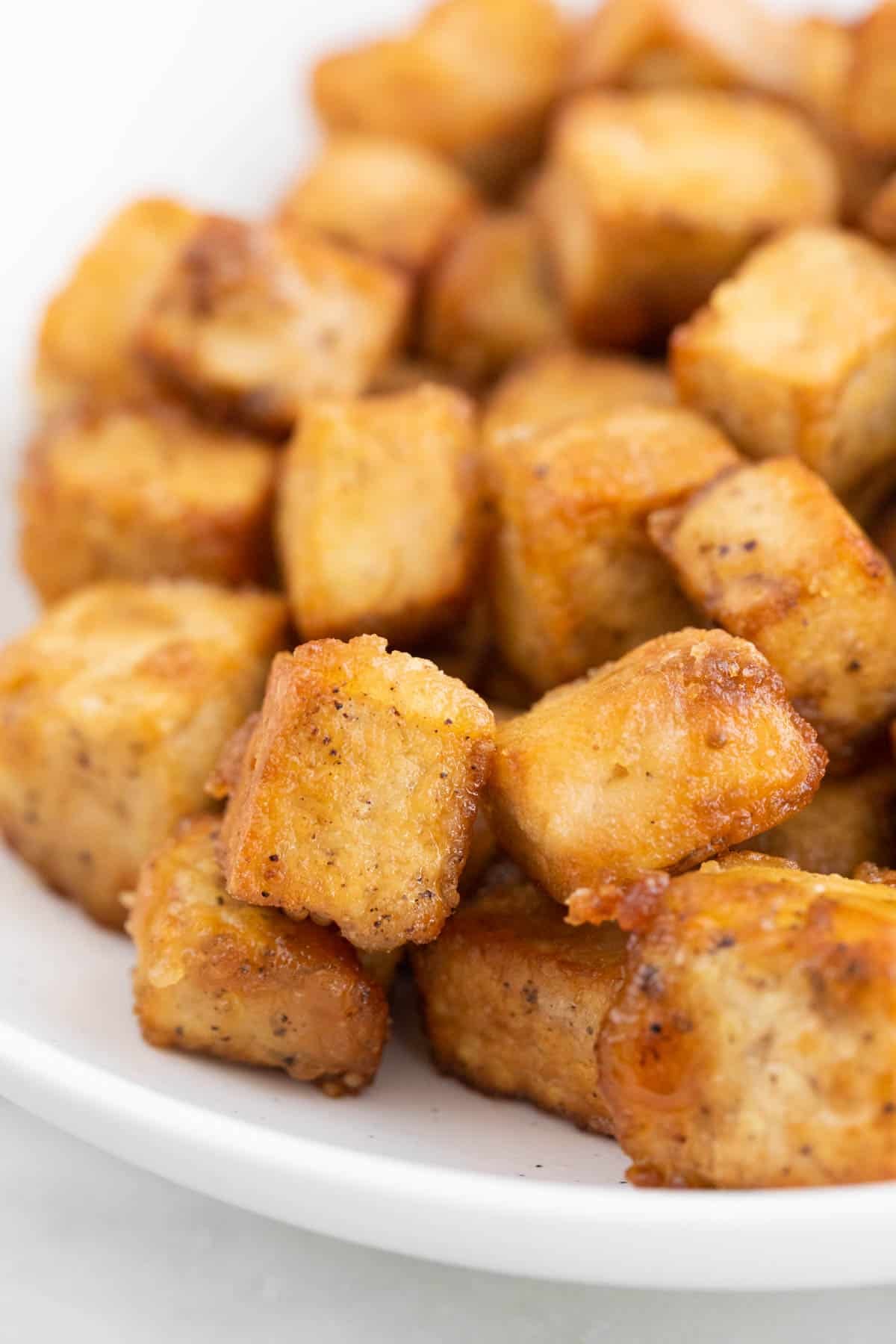 Golden brown fried tofu cubes on a plate.