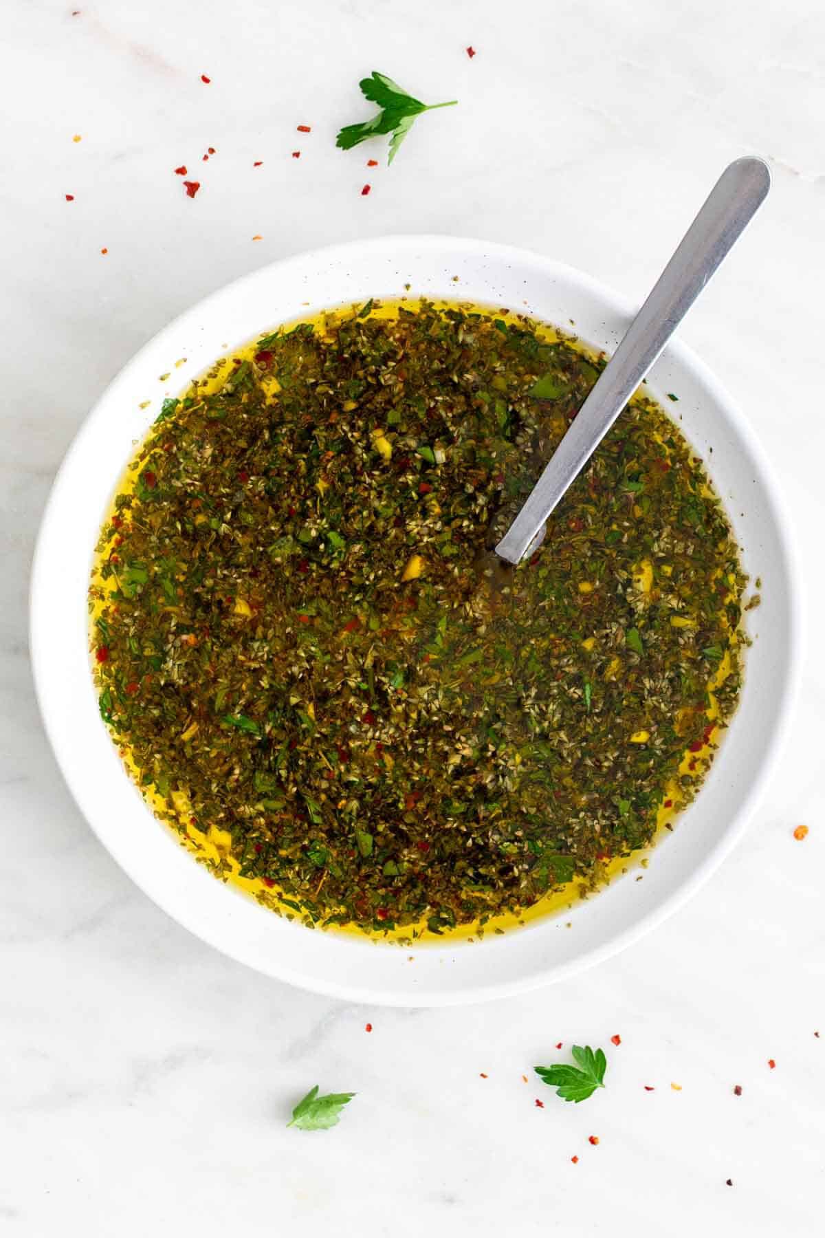 Chimichurri sauce in a small bowl with a spoon.