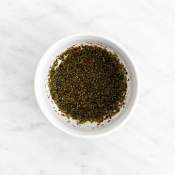Dried oregano and red pepper flakes in a bowl with hot water for chimichurri.