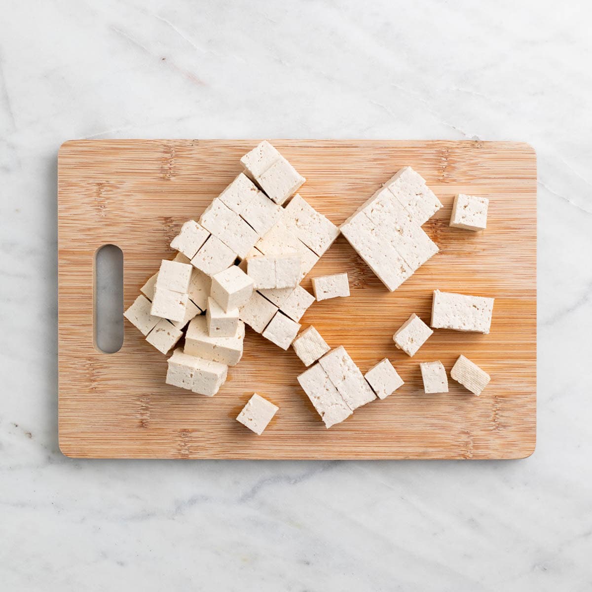 Tofu cubes on a cutting board.