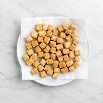 Crispy deep fried tofu on a plate with paper towel.