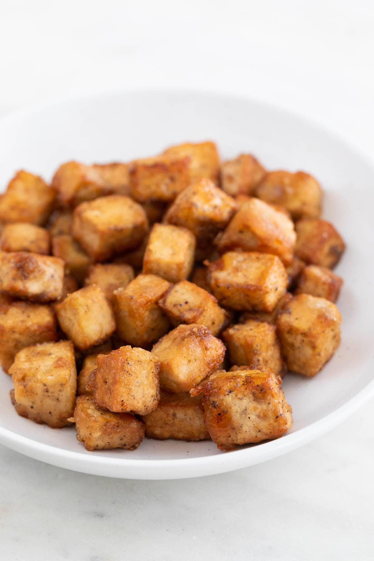 Crispy tofu cubes on a plate, golden and crunchy.