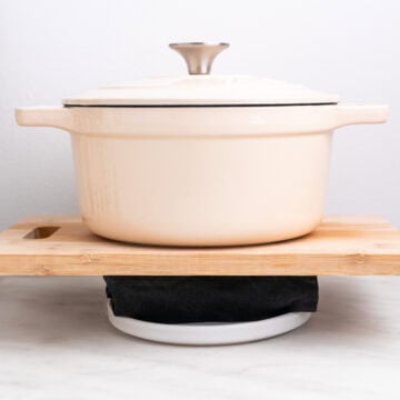 Tofu wrapped in a towel pressed with a pot.