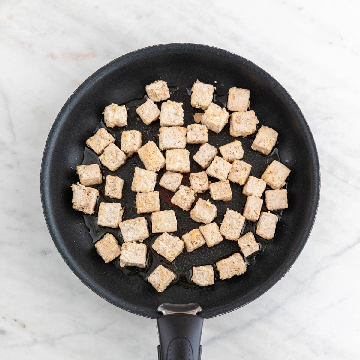 Tofu cooking in a pan.