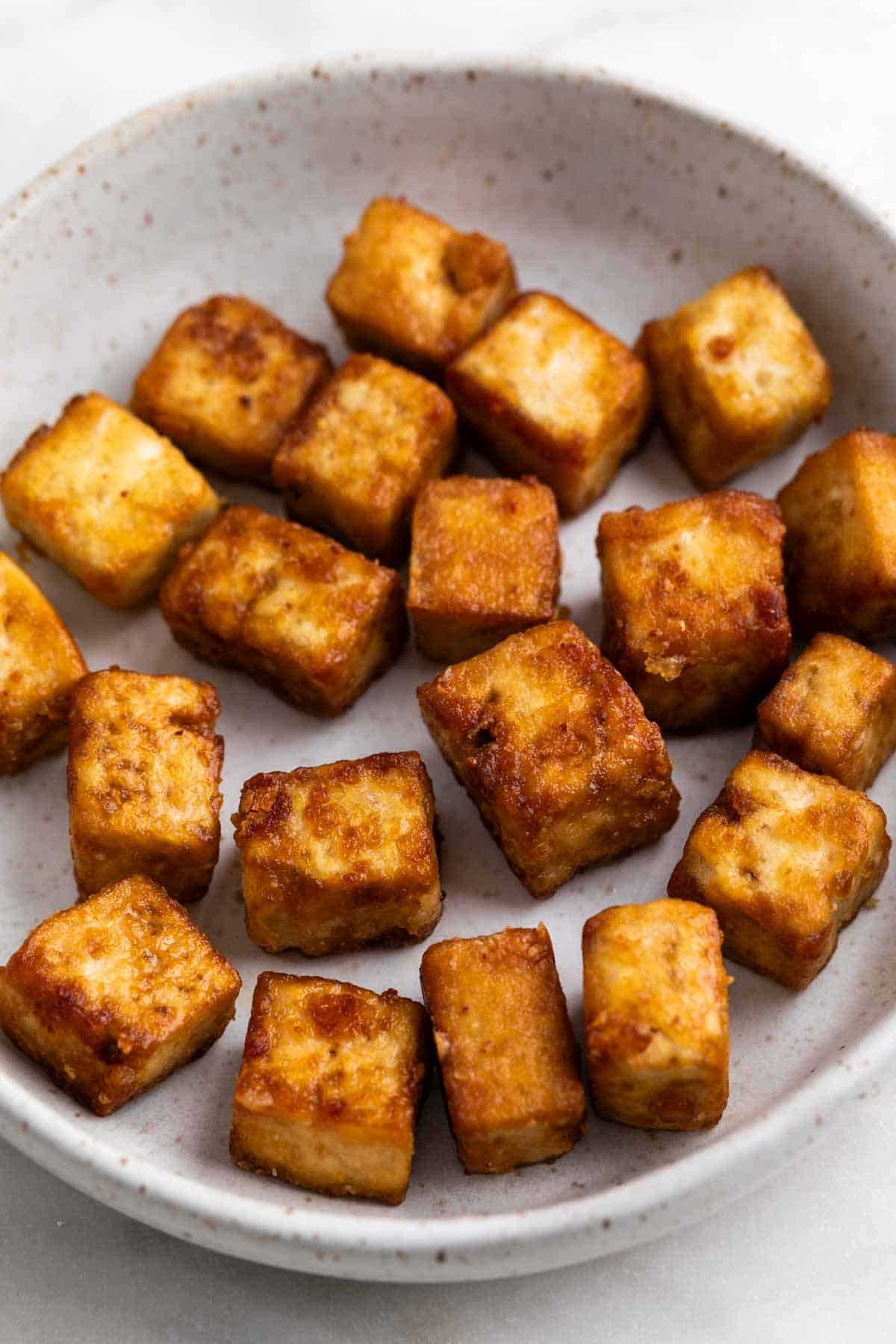 Crispy pan fried tofu cubes on a plate.