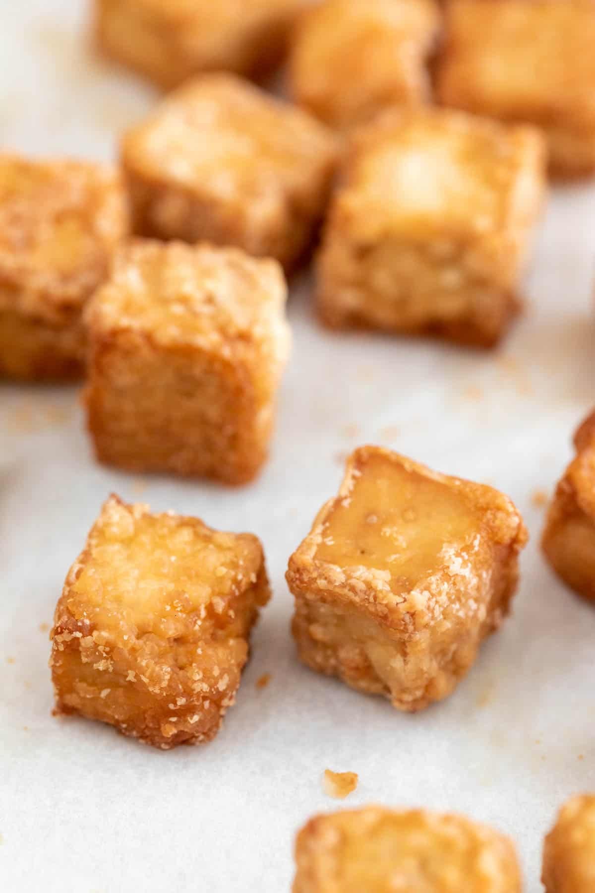 Baked tofu cubes on a lined baking sheet.