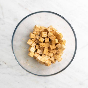 Tofu cubes coated with marinade in a bowl.