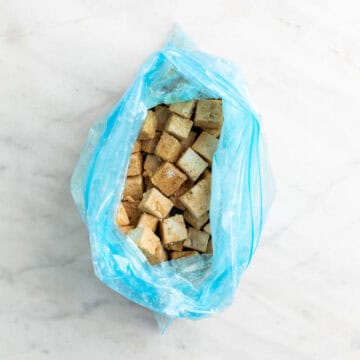 Tofu cubes coated with cornstarch in a zip-top bag.