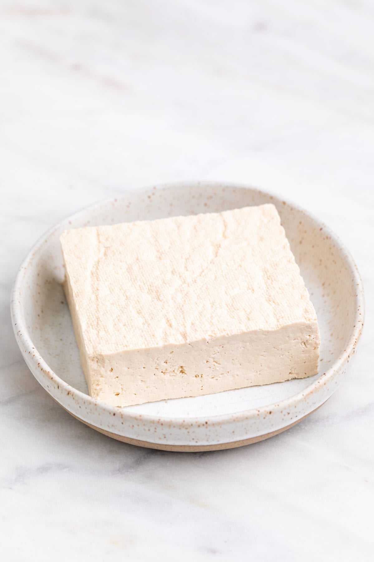 Pressed tofu block on a plate.
