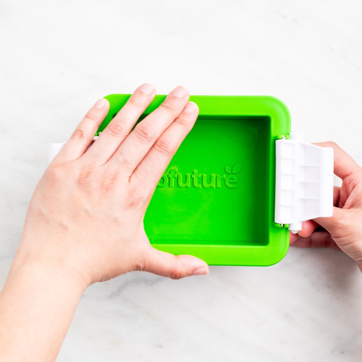 Closing a tofu press to press tofu.