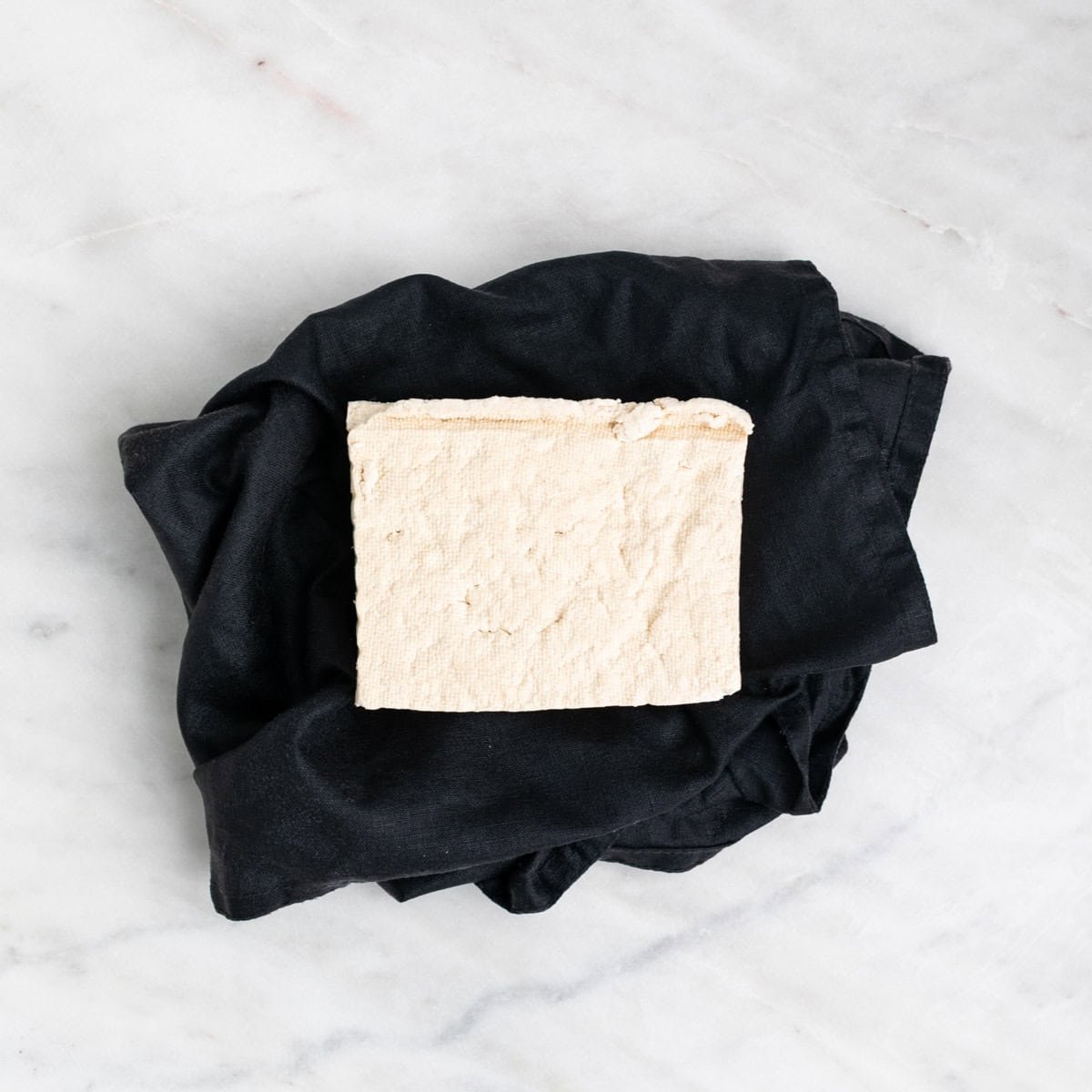 Pressed tofu block on an open kitchen towel.