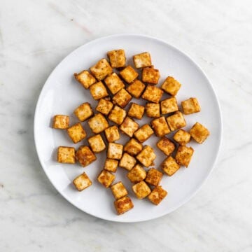 Crispy cooked tofu cubes on a plate.