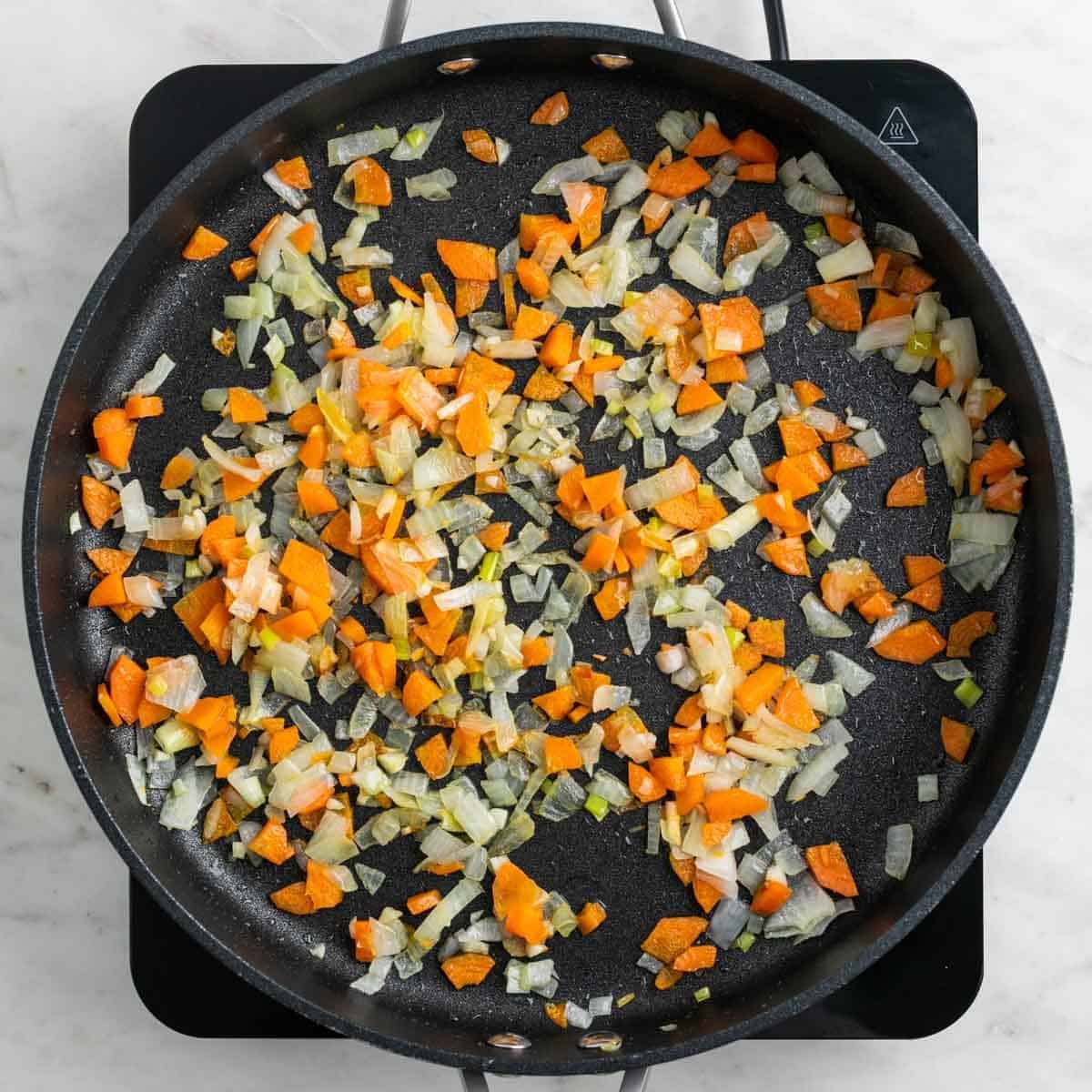 Garlic onion and carrot cooking in a pan.