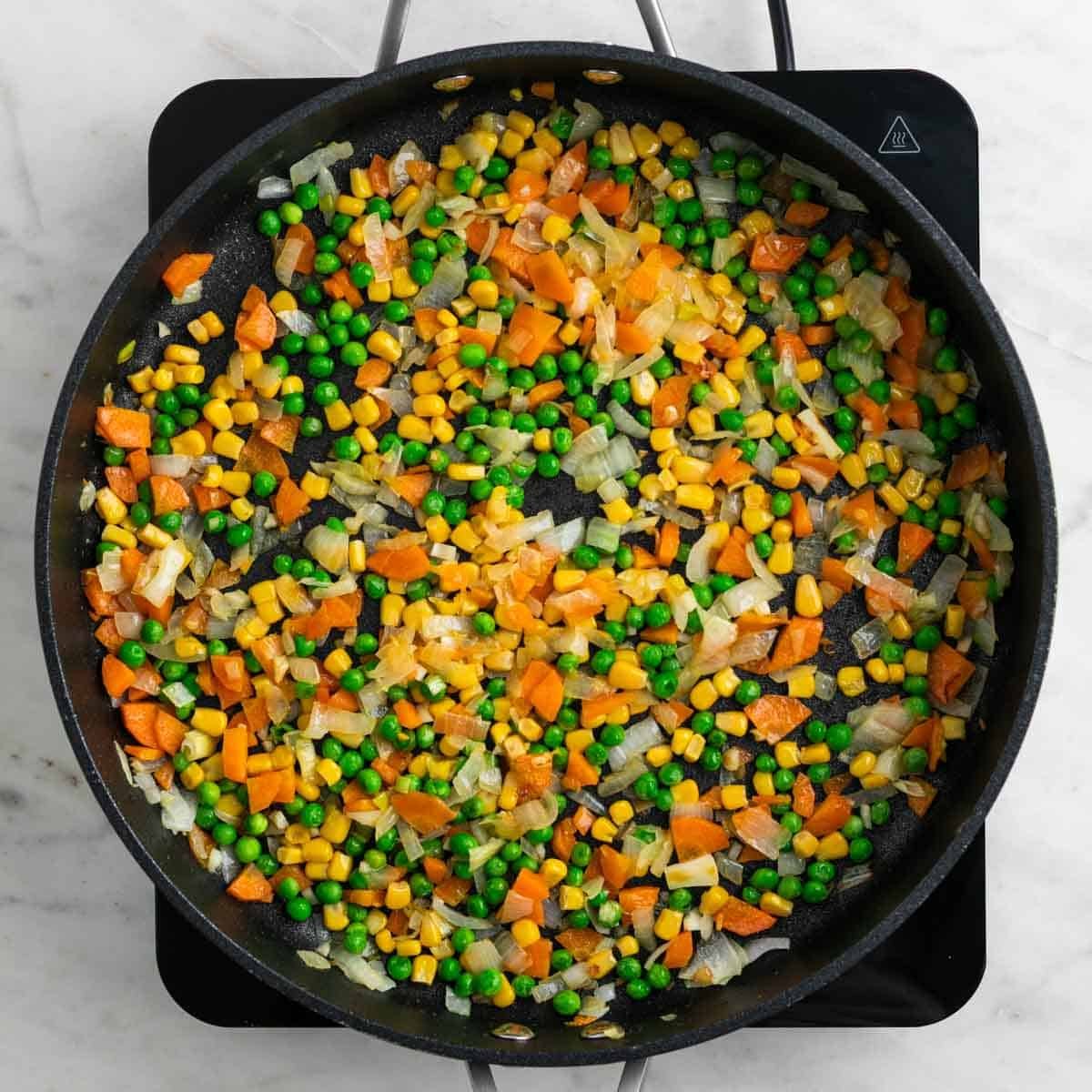 Peas and corn cooking with vegetables.