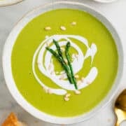 Vegan asparagus soup served with bread and a spoon on the side.