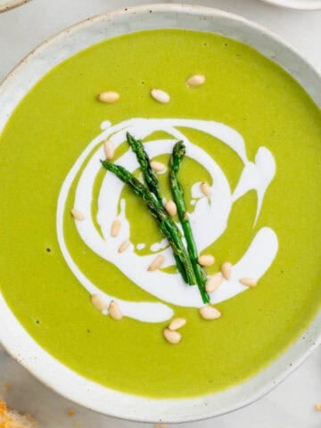 Vegan asparagus soup served with bread and a spoon on the side.