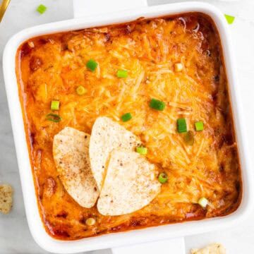 Vegan buffalo chicken dip with scallions and tortilla chips for dipping.