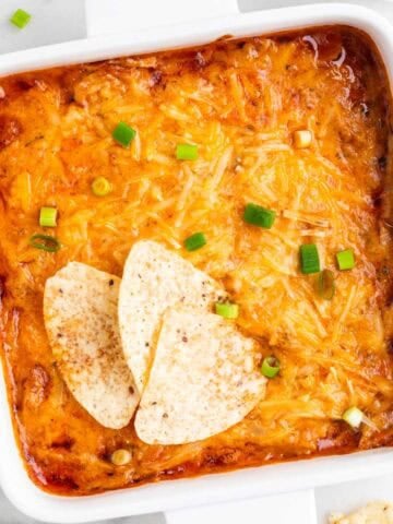 Vegan buffalo chicken dip with scallions and tortilla chips for dipping.