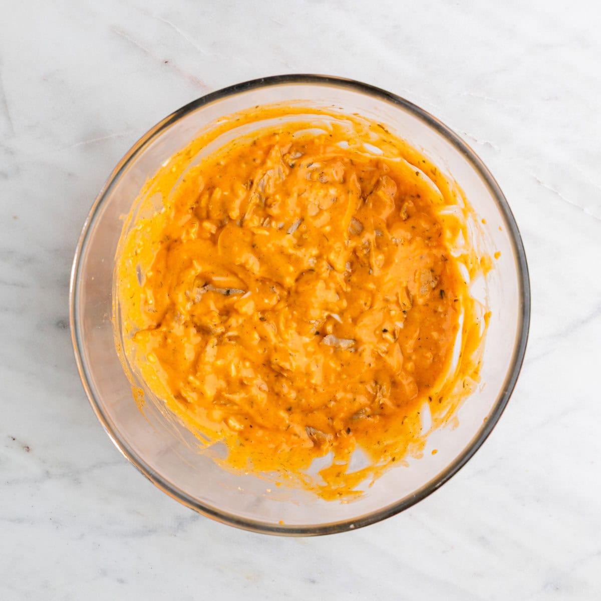 Mixing vegan buffalo chicken dip ingredients in a bowl.