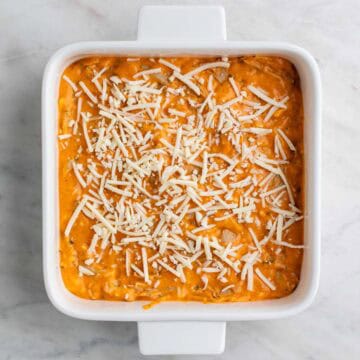 Vegan buffalo chicken dip topped with shredded vegan cheese.
