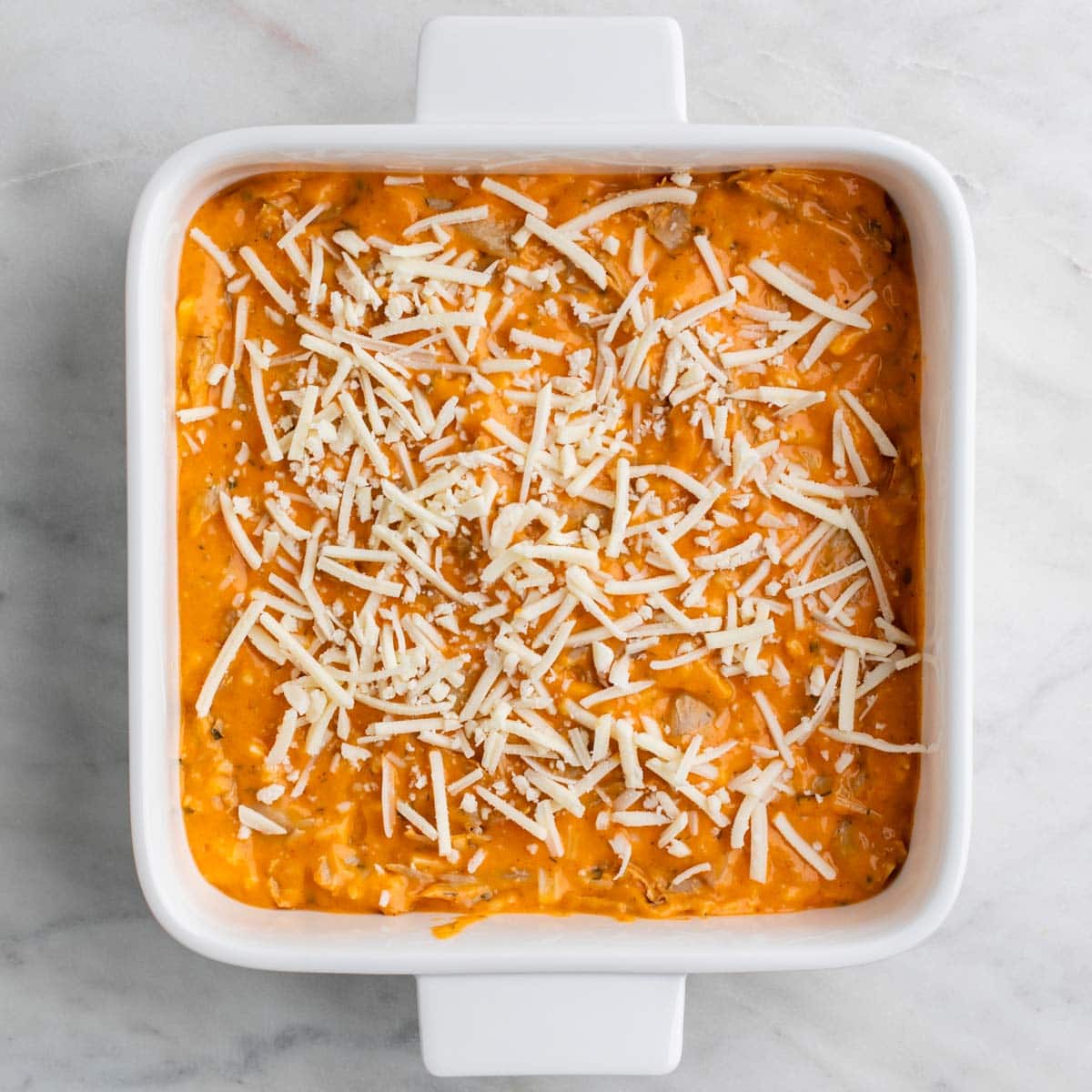 Vegan buffalo chicken dip topped with shredded vegan cheese.