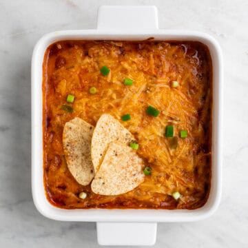 Vegan buffalo chicken dip topped with scallions and served with tortilla chips.