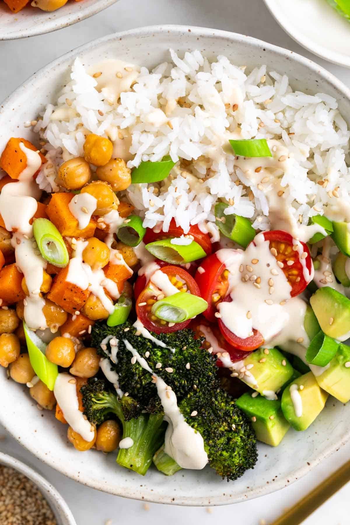 Vegan rice bowl with fork, sesame seeds, and green onions.