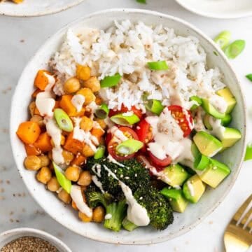 Close-up of a vegan rice bowl topped with sesame seeds and green onions.