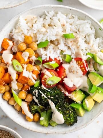 Close-up of a vegan rice bowl topped with sesame seeds and green onions.