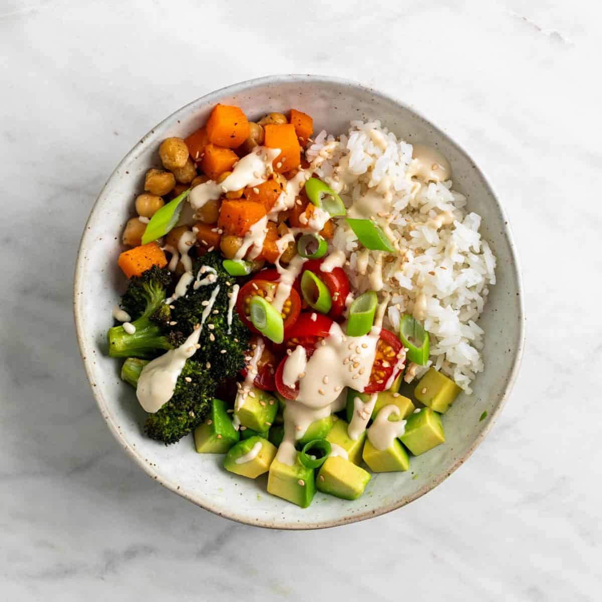 Vegan rice bowl topped with green onions and sesame seeds.