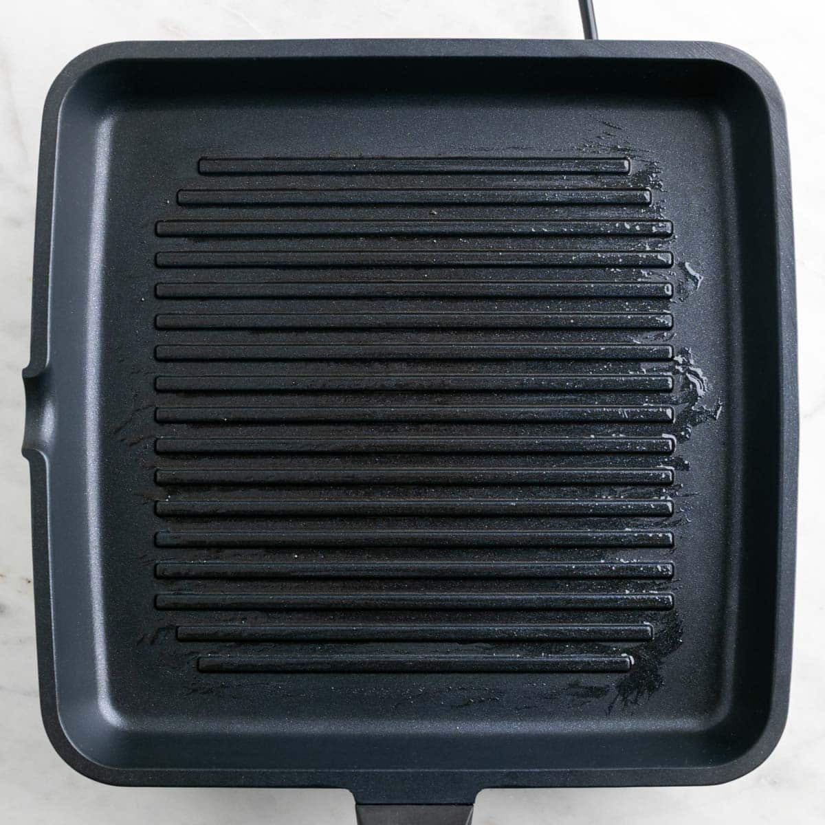 Grill pan preheating on the stove with a light layer of oil.