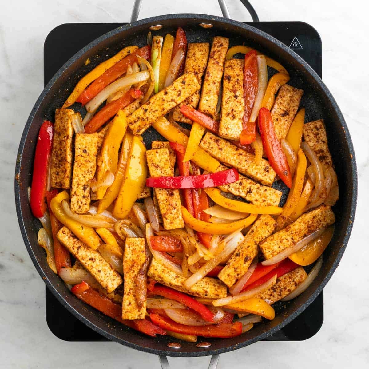 Tofu and vegetables cooking together in a skillet