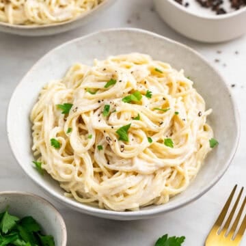 Two servings of spaghetti with silken tofu pasta sauce topped with parsley and black pepper