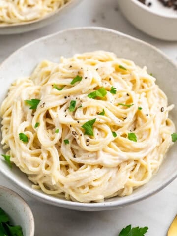 Two servings of spaghetti with silken tofu pasta sauce topped with parsley and black pepper
