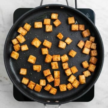 Tofu cooking in a pan until golden and crispy