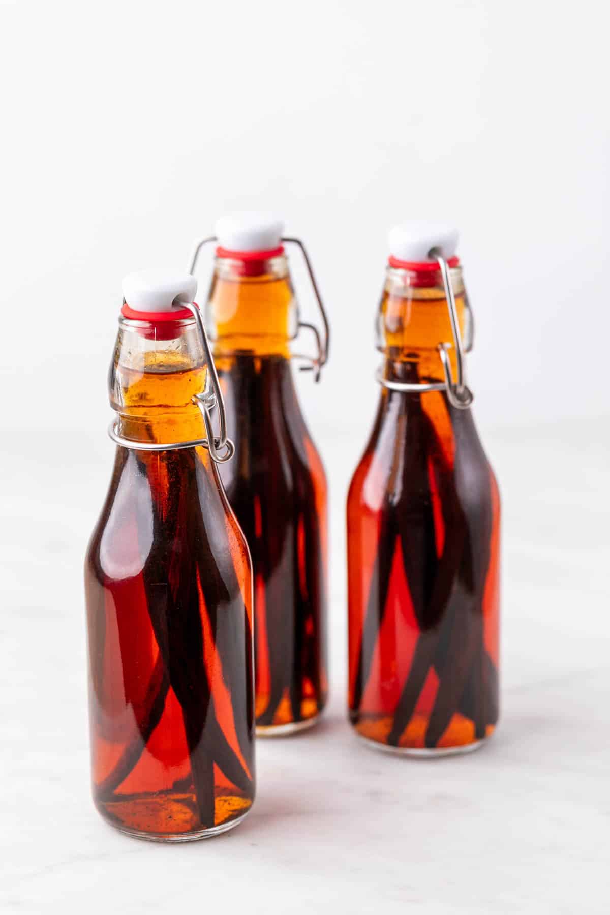 Bottles of homemade vanilla extract with vanilla beans in dark liquid after 3 months