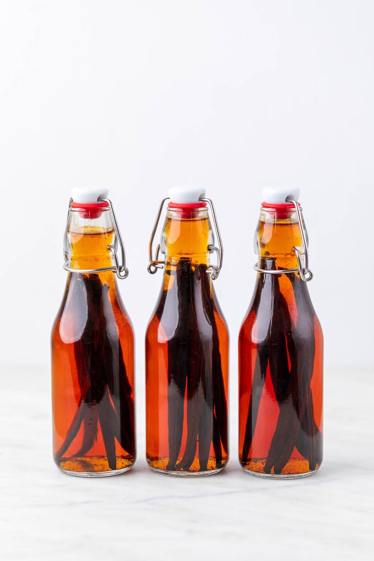 Three bottles of homemade vanilla extract after 3 months with vanilla beans inside