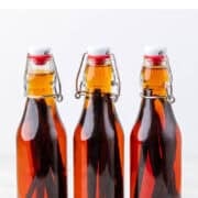 Three jars of homemade vanilla extract with vanilla beans fully infused