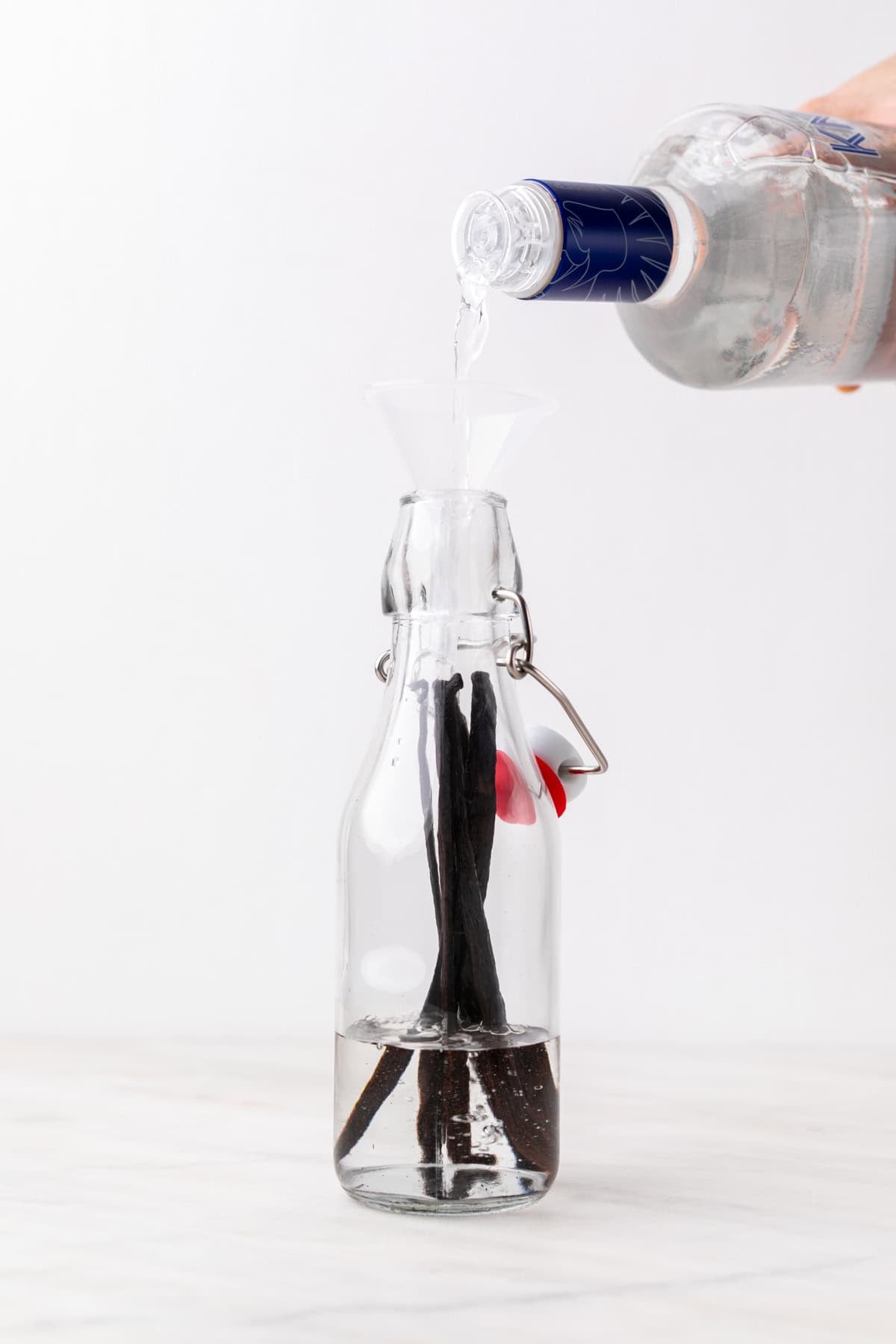 Pouring vodka into a glass bottle with vanilla beans inside