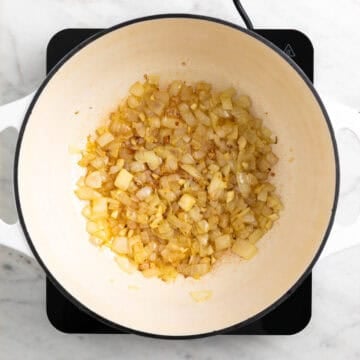 Cooked onion and garlic in a pot for vegan carrot soup