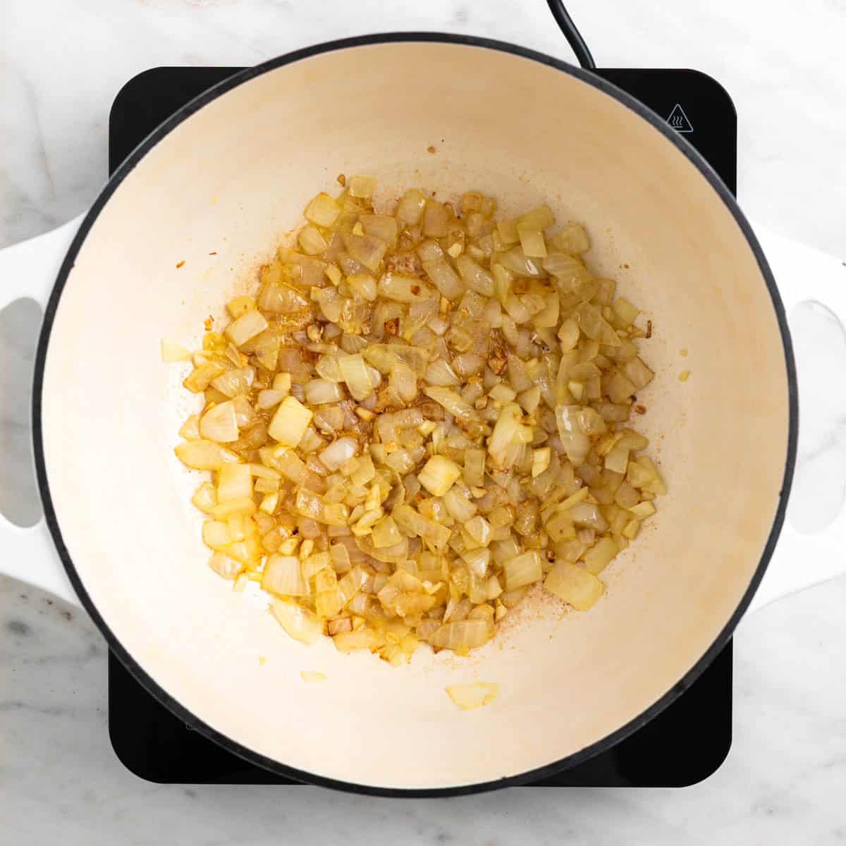 Cooked onion and garlic in a pot for vegan carrot soup